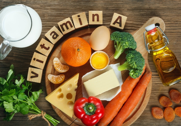un ensemble d'aliments est posé sur une table et des bloc de bois forment le mot "vitamine A"